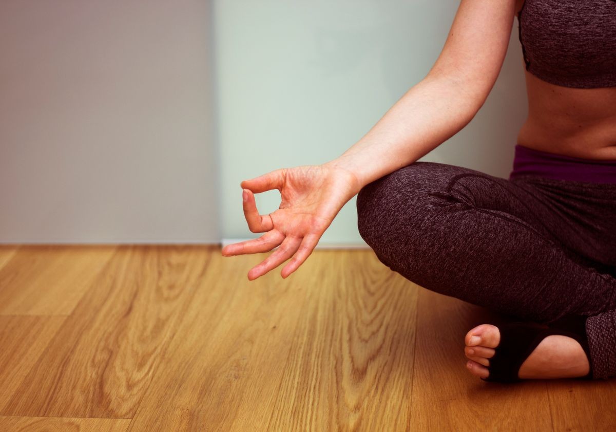 Female instructor yoga teacher teaching asana pose with mudra hand posture.